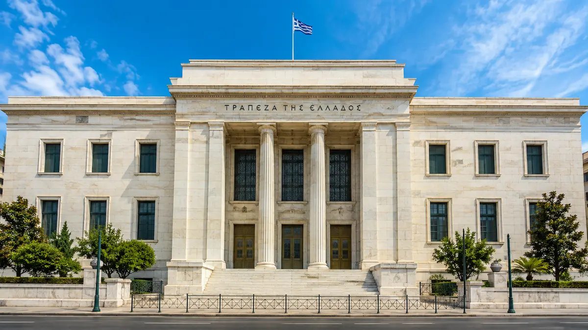 Εξωτερική άποψη του κτιρίου της Τράπεζας της Ελλάδος, με τη χαρακτηριστική μαρμάρινη πρόσοψη και την ελληνική σημαία